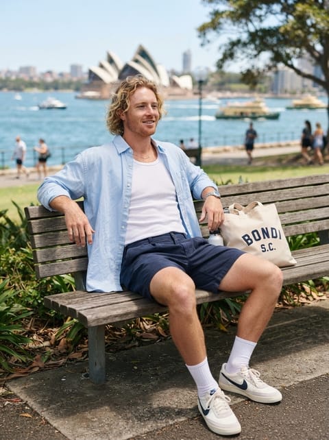 SKIPIKS AIファッション写真 — casual, minimalist — 空色のシャツとホワイトタンクトップの組み合わせが涼しげで爽やかな印象を与えるルックです。ネイビーのショートパンツとキャンバスバッグでカジュアルなスタイルをプラス
