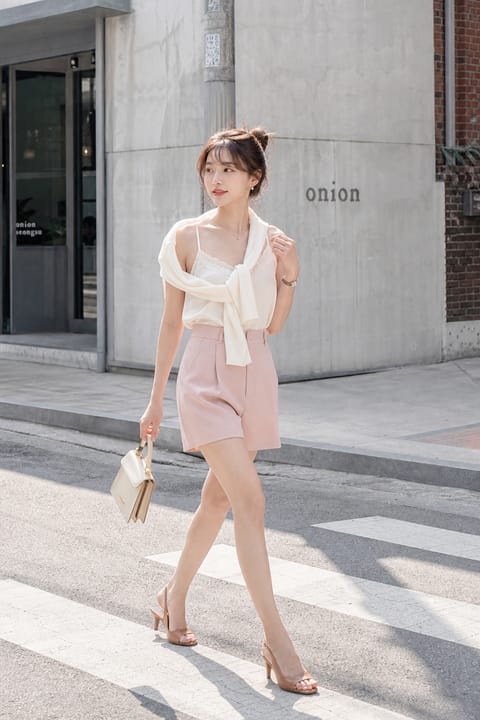 SKIPIKS AI fashion editorial — feminine, chic — This look features a cream sleeveless top paired with pink shorts, creating a ro